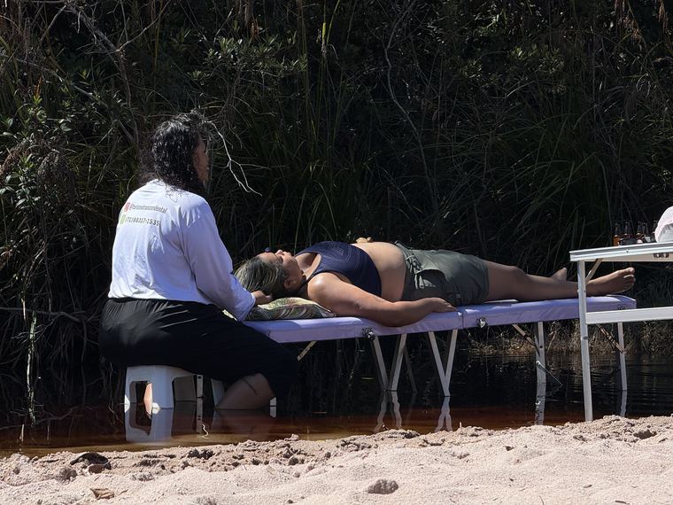 Terapeuta atendendo paciente deitada em maca à beira do Rio Mucugê
